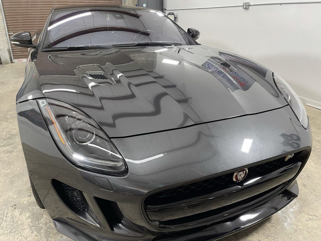 A black jaguar f type is parked in a garage.