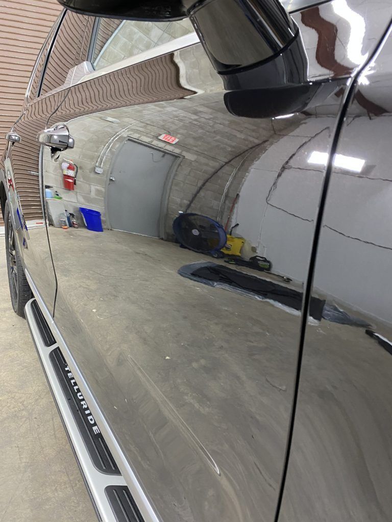 A black car is parked in a garage next to a brick wall.