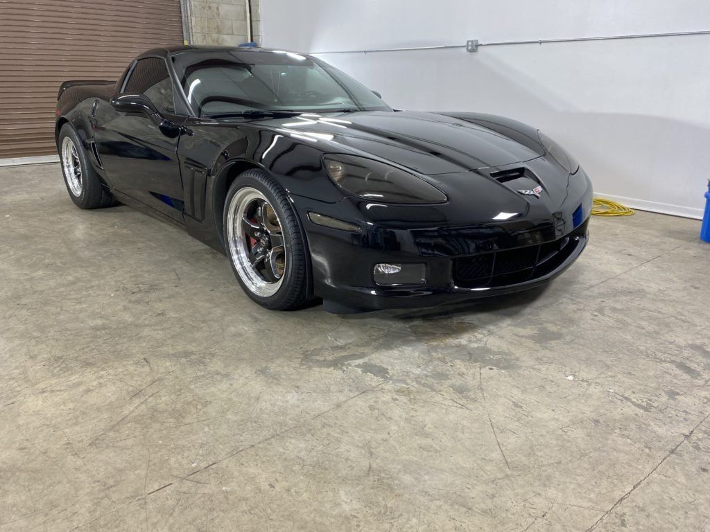 A black corvette is parked in a garage.