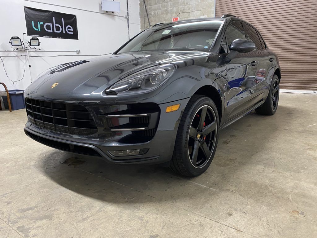 A gray porsche macan turbo is parked in a garage.