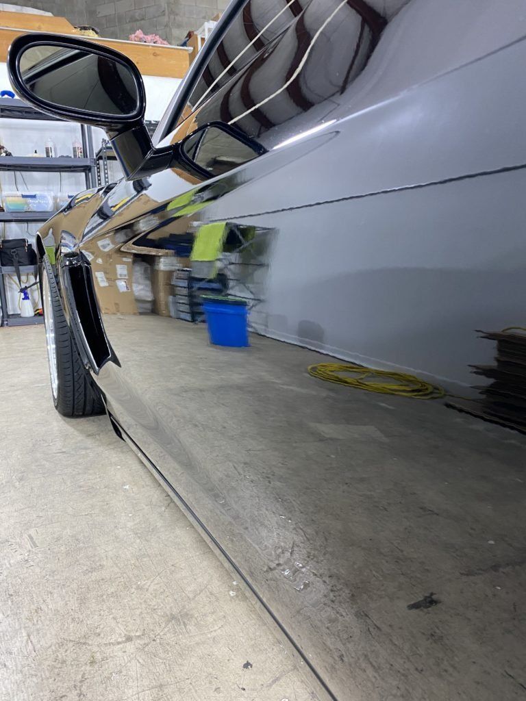A black car is parked in a garage with a rear view mirror.