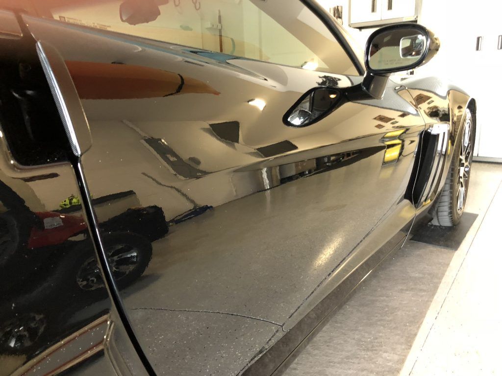 A black sports car is parked in a garage.