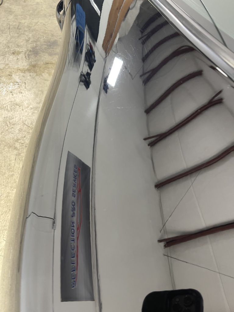 A close up of a car with a reflection of a building in the mirror.