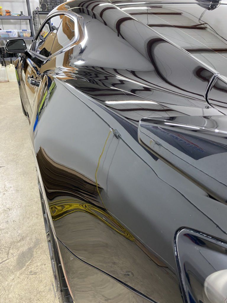 A close up of a black car in a garage.