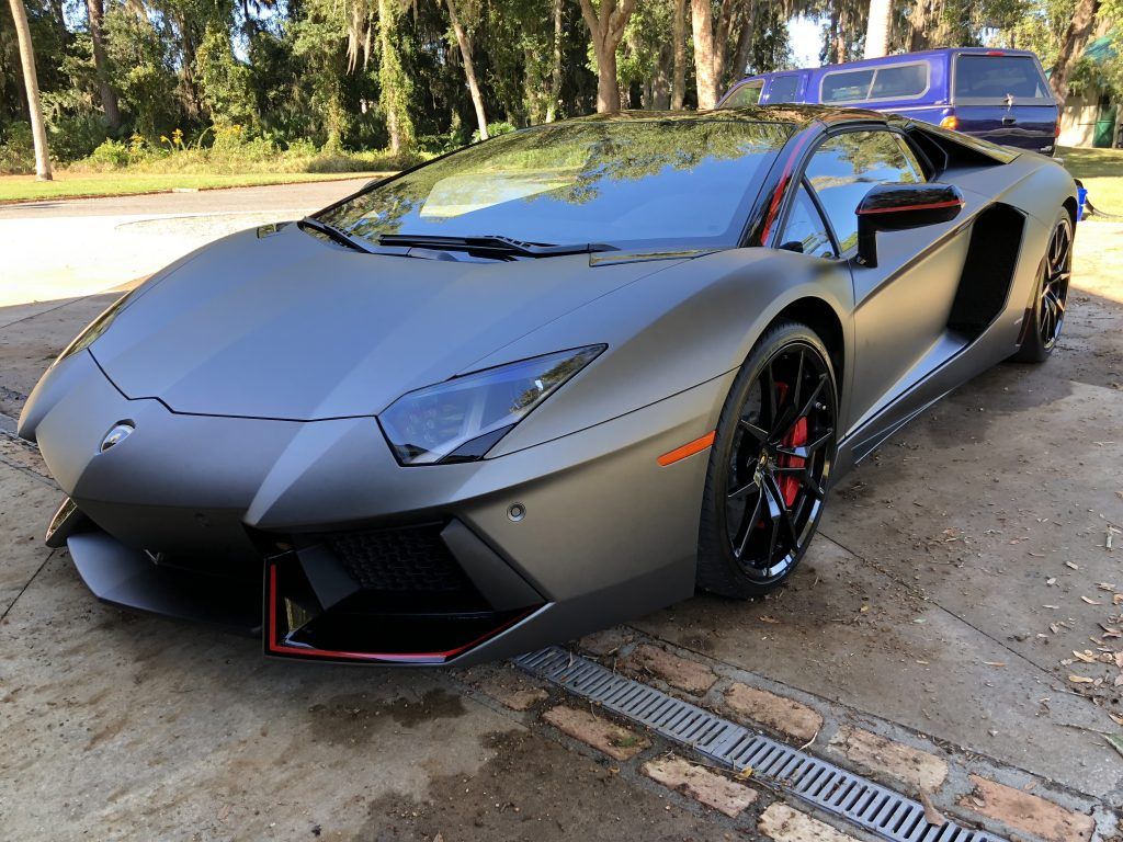 A black lamborghini aventador is parked on the side of the road.