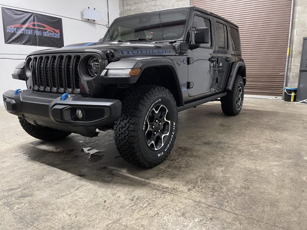A black jeep wrangler is parked in a garage.