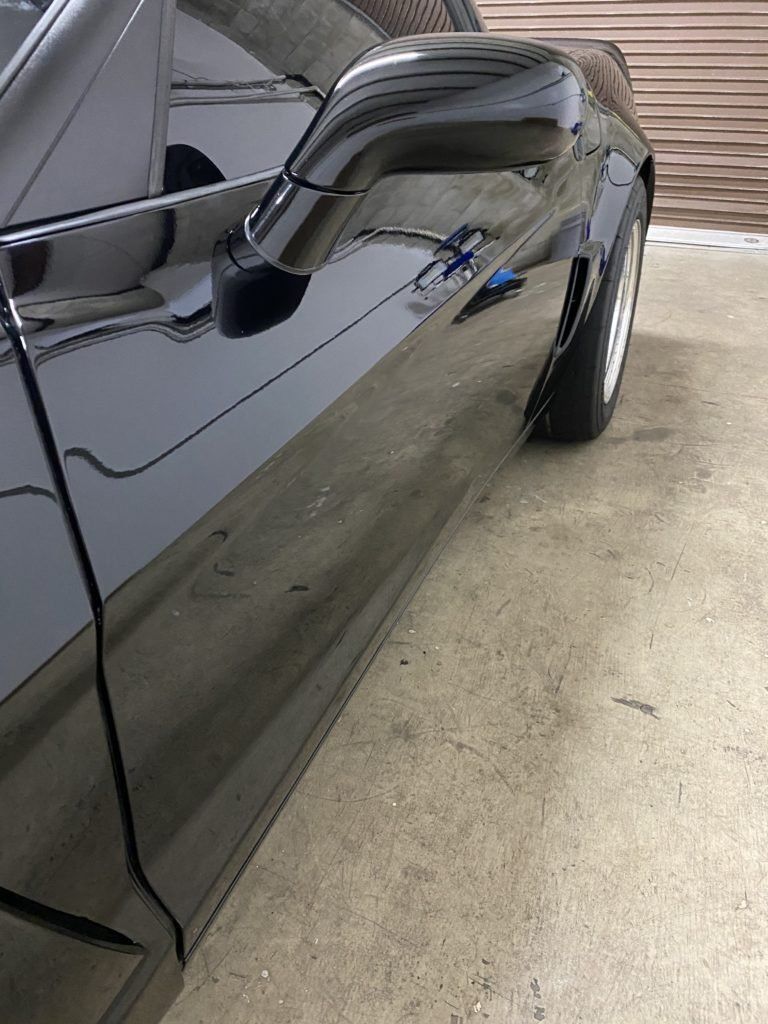 A black car is parked on a concrete floor in a garage.