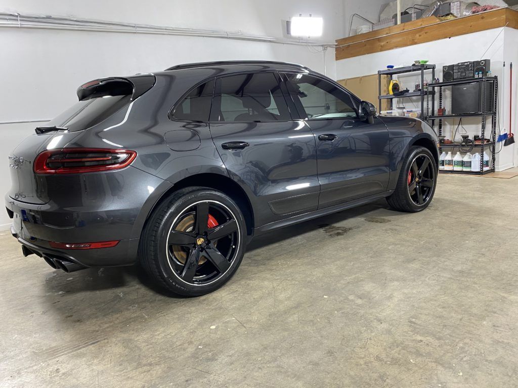 A gray porsche macan is parked in a garage.