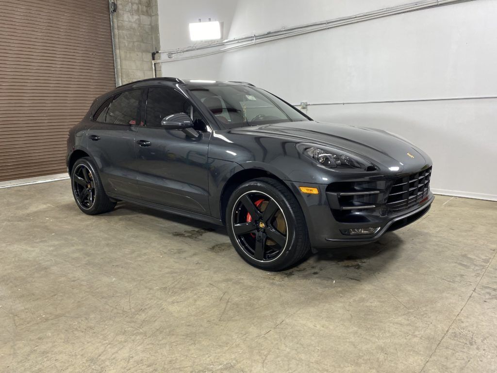 A gray porsche macan turbo is parked in a garage.