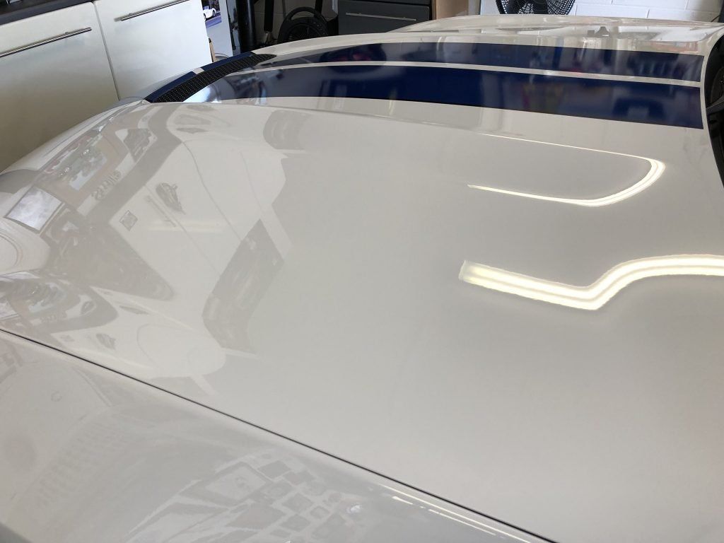 A close up of a white car 's hood in a garage.