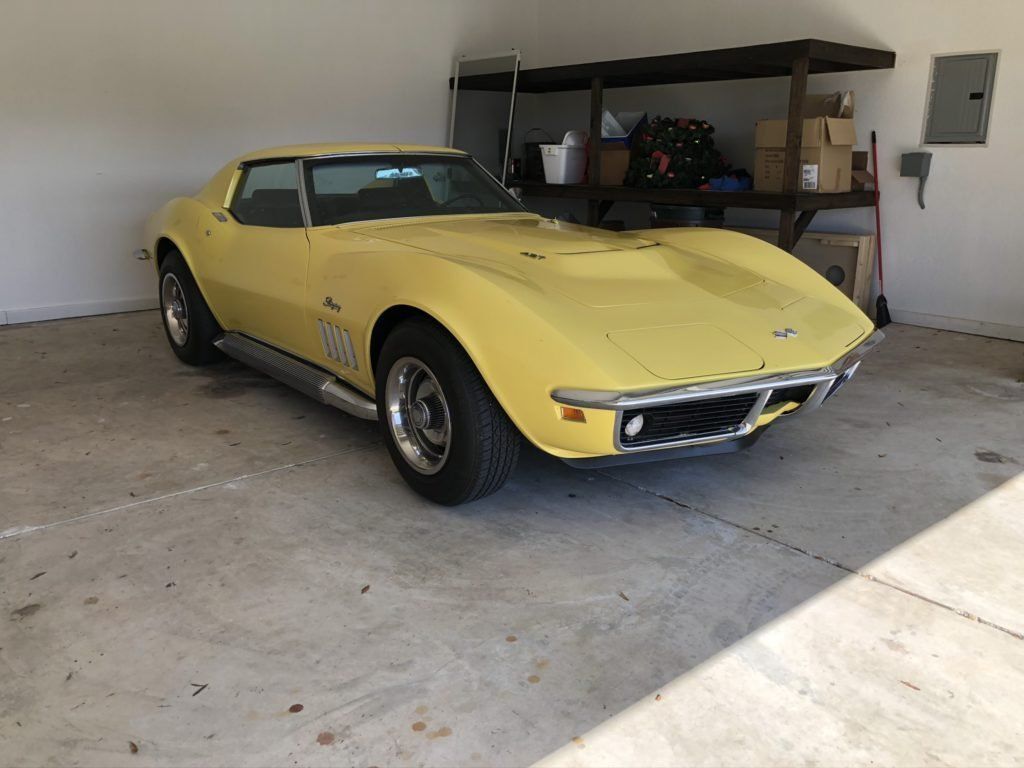 A yellow corvette is parked in a garage.