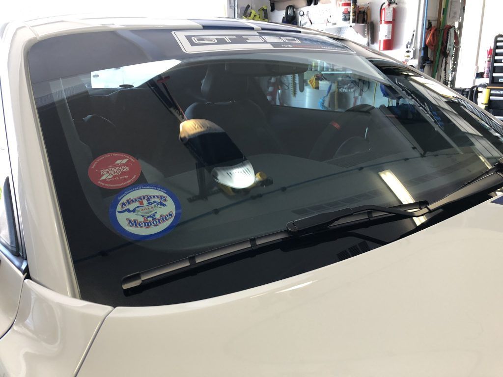A white car with a sticker on the windshield is parked in a garage.