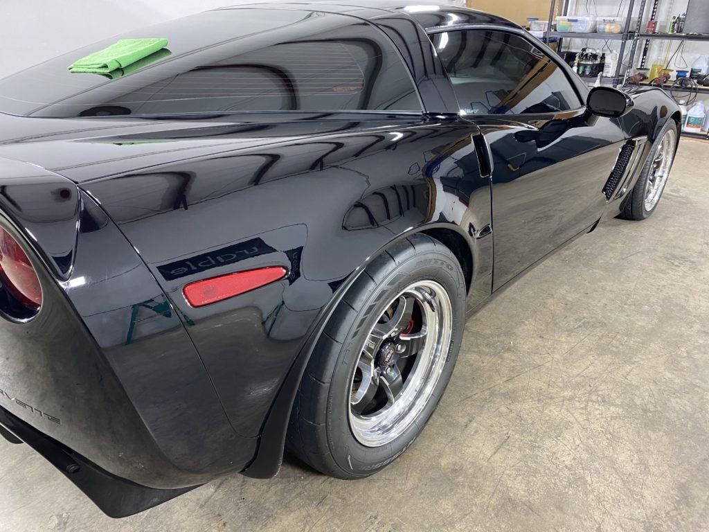 A black sports car is parked in a garage.