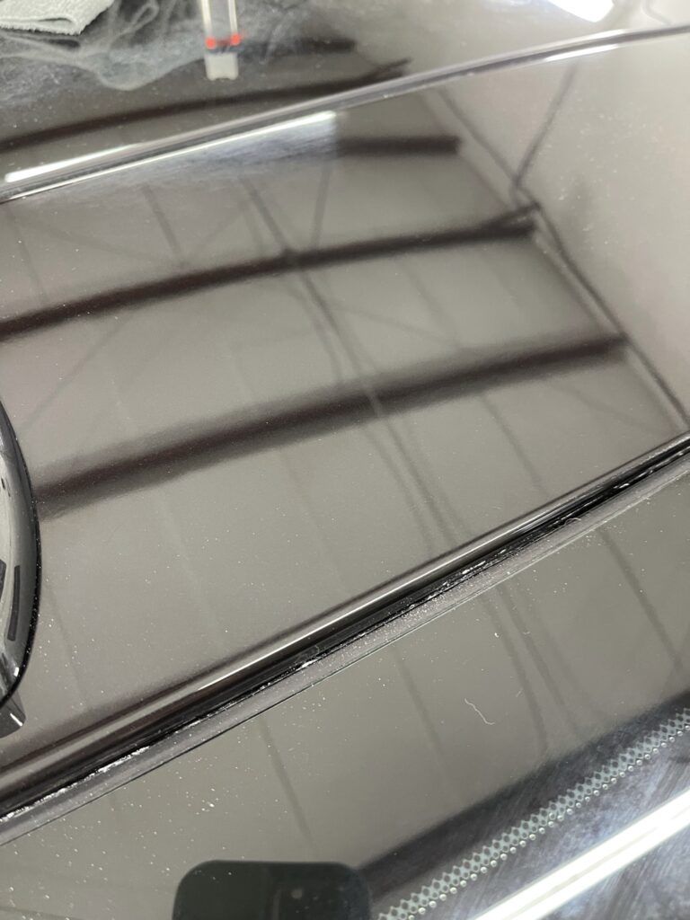 A close up of a car 's hood with a reflection of a building in it.