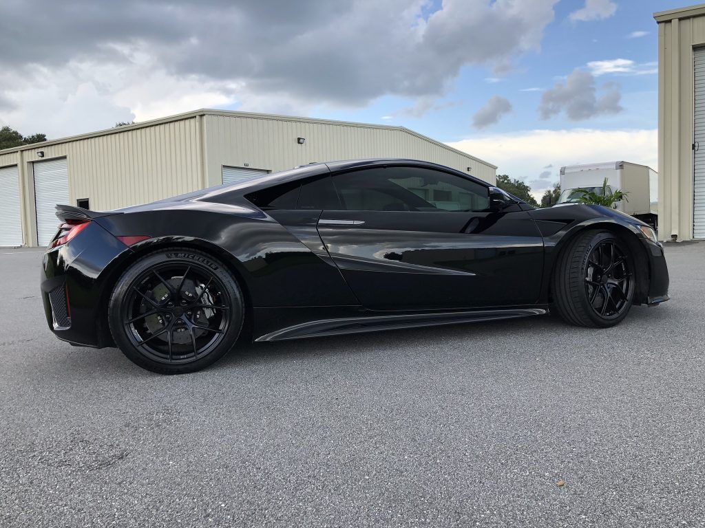 A black sports car is parked in front of a building.