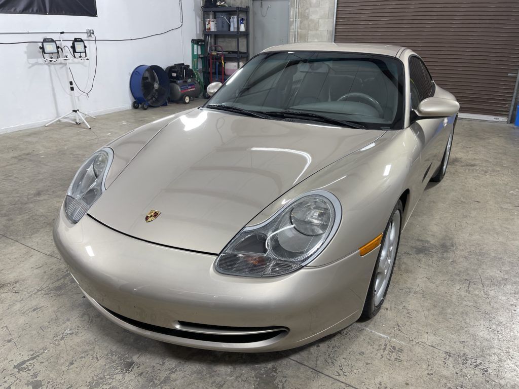 A silver porsche 911 is parked in a garage.
