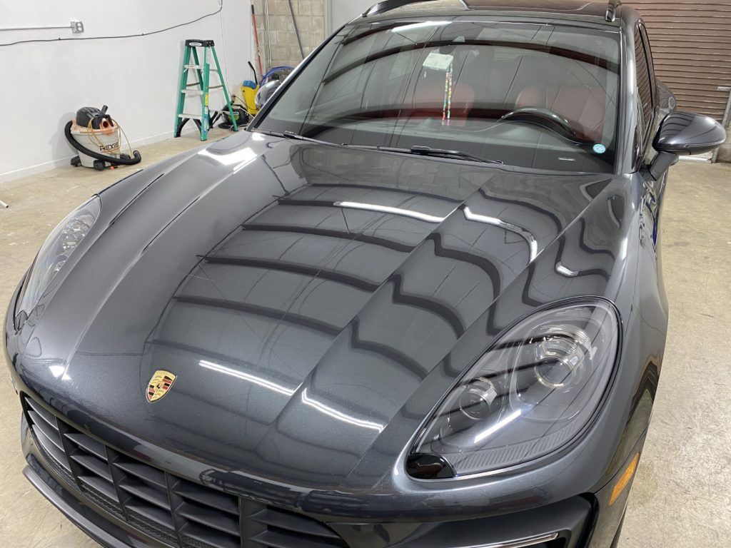 A gray porsche macan is parked in a garage.