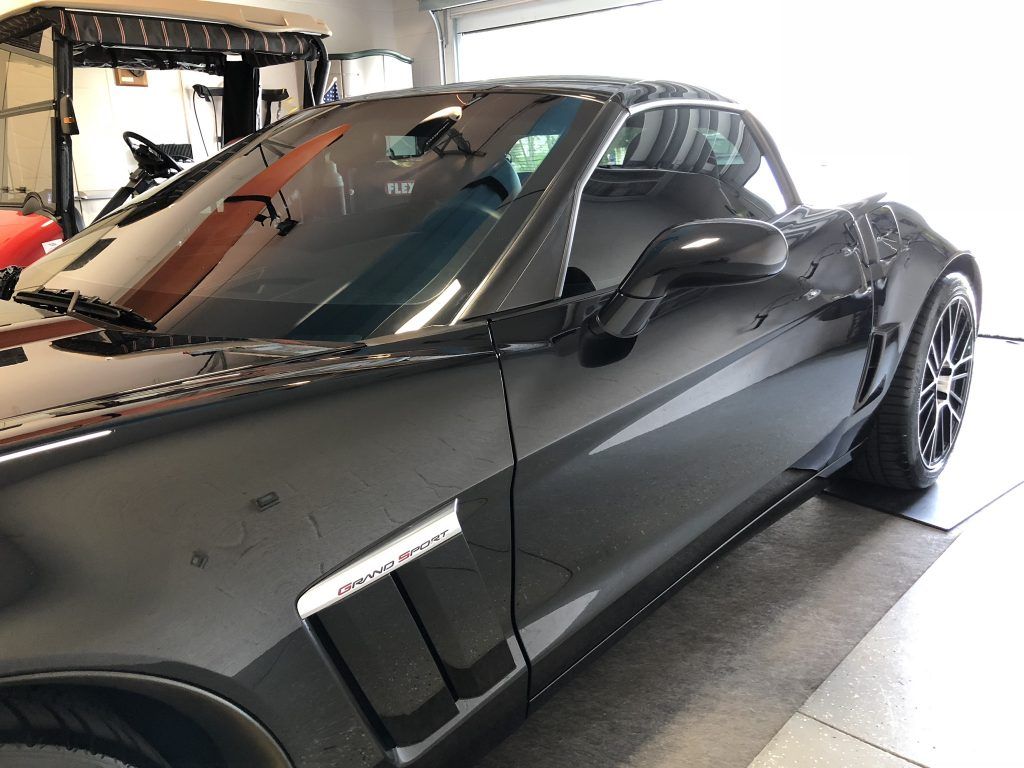 A black sports car is parked in a garage.