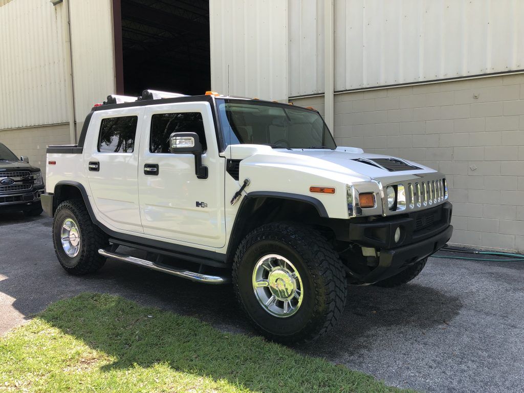 A white hummer h2 is parked in front of a building.