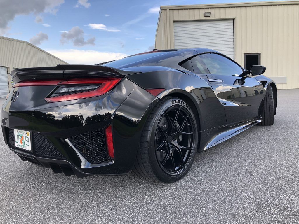 A black sports car is parked in front of a building.