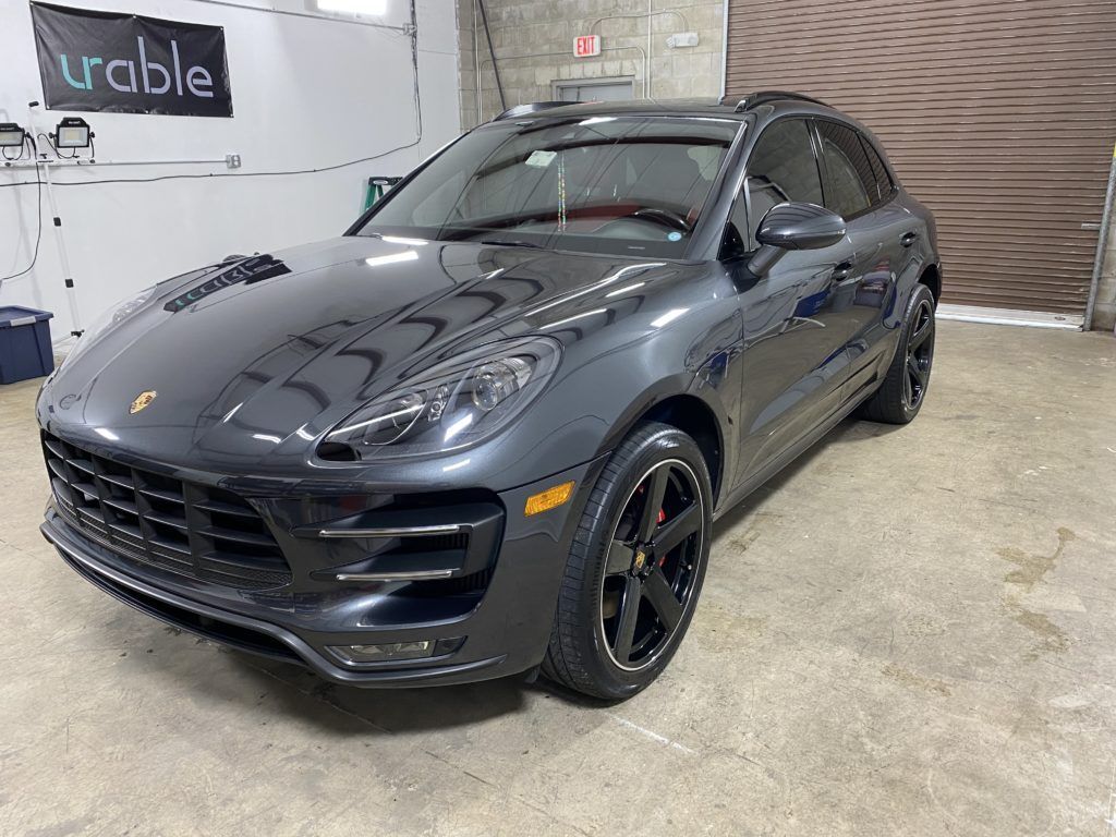 A gray porsche macan turbo is parked in a garage.