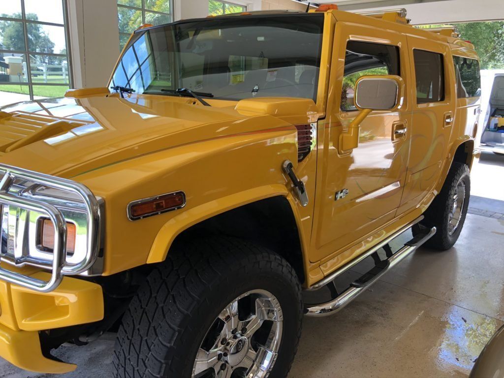 A yellow hummer is parked in a garage.