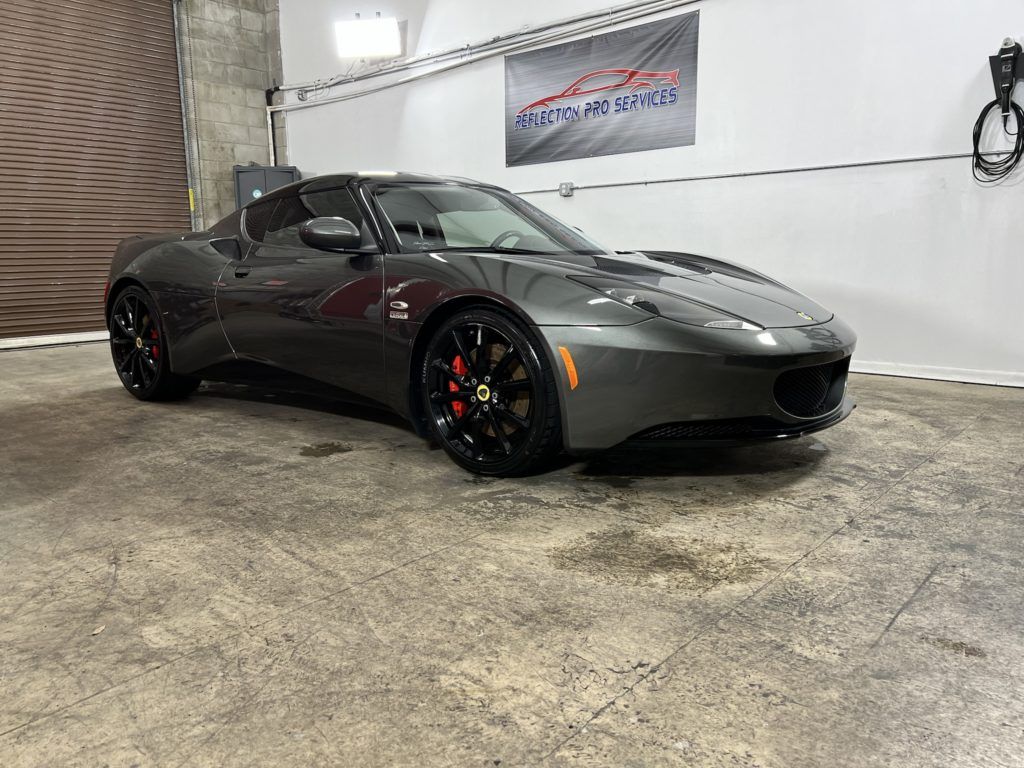 A gray sports car is parked in a garage.