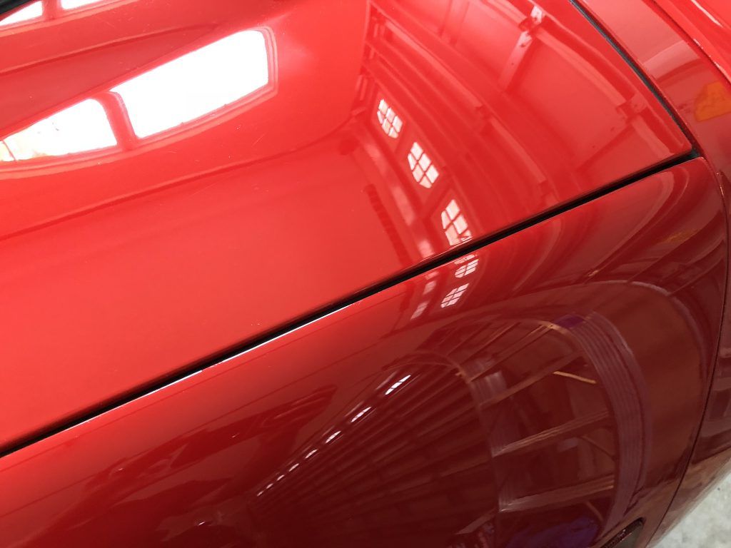A close up of a red car 's fender in a garage.