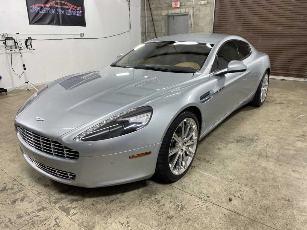 A silver aston martin sports car is parked in a garage.