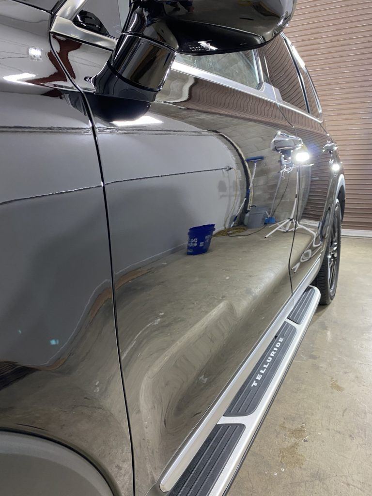 A black car with side steps is parked in a garage.