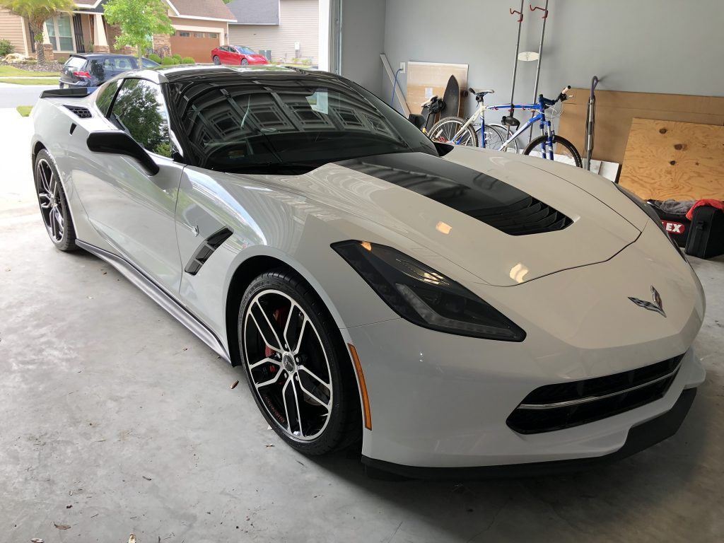 A white corvette is parked in a garage.