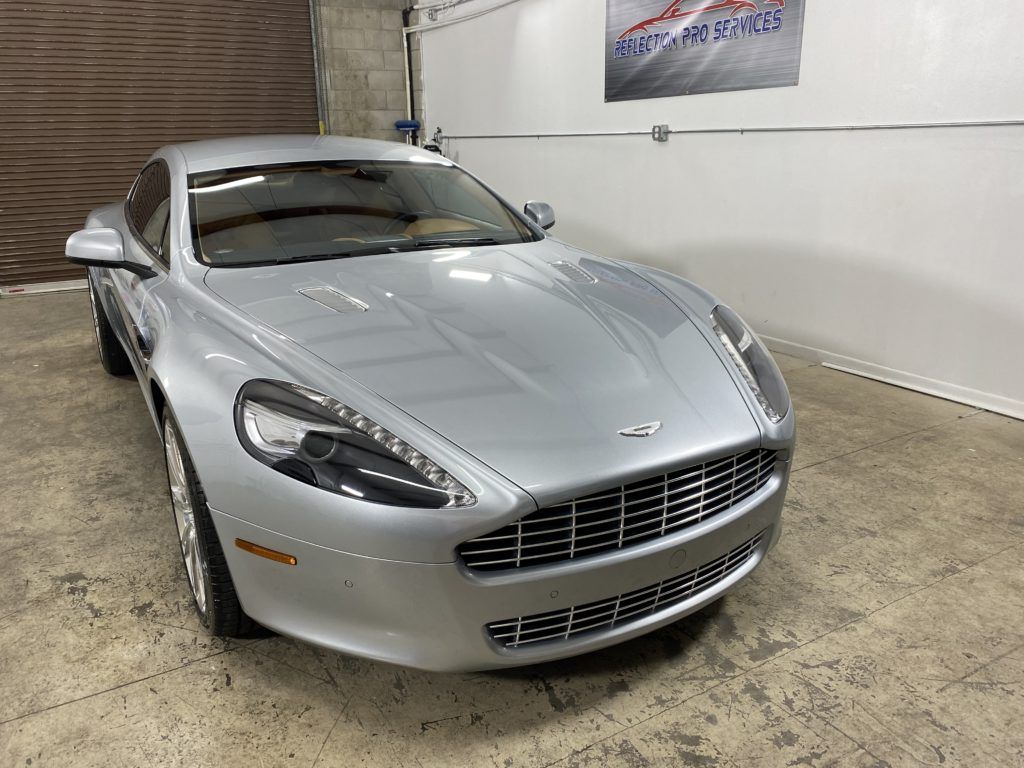 A silver aston martin sports car is parked in a garage.