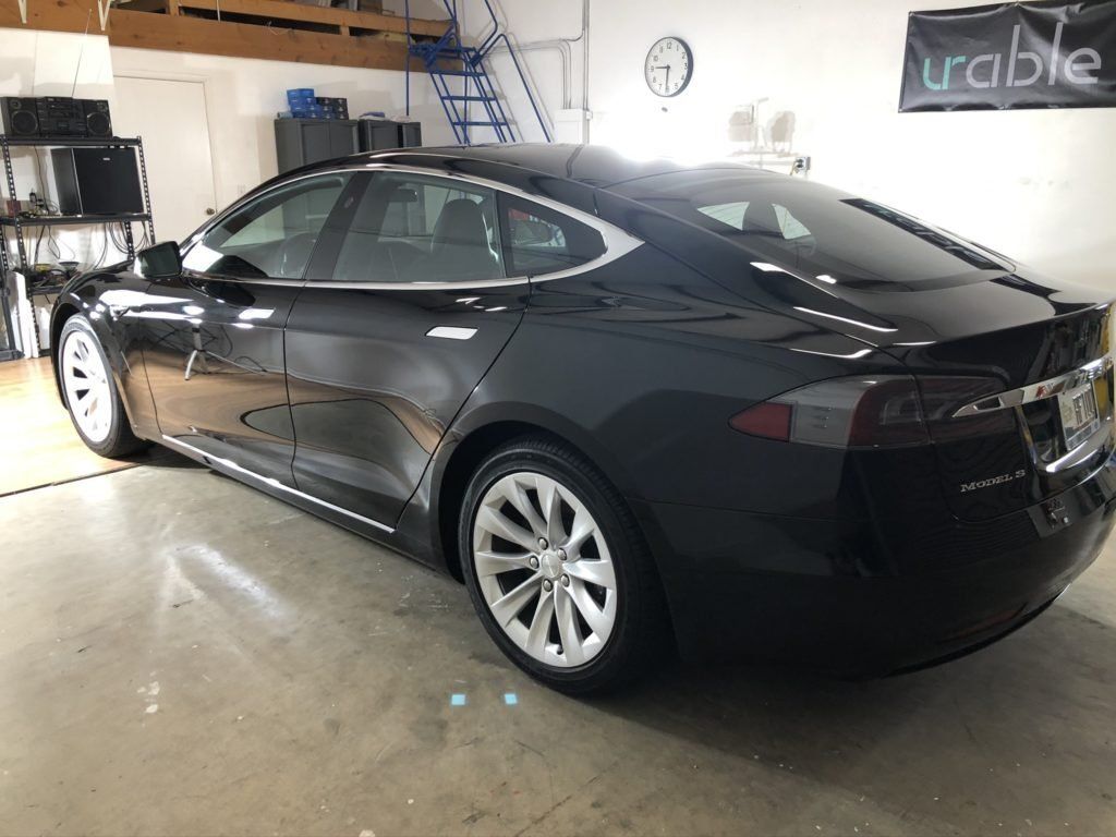 A black tesla model s is parked in a garage.