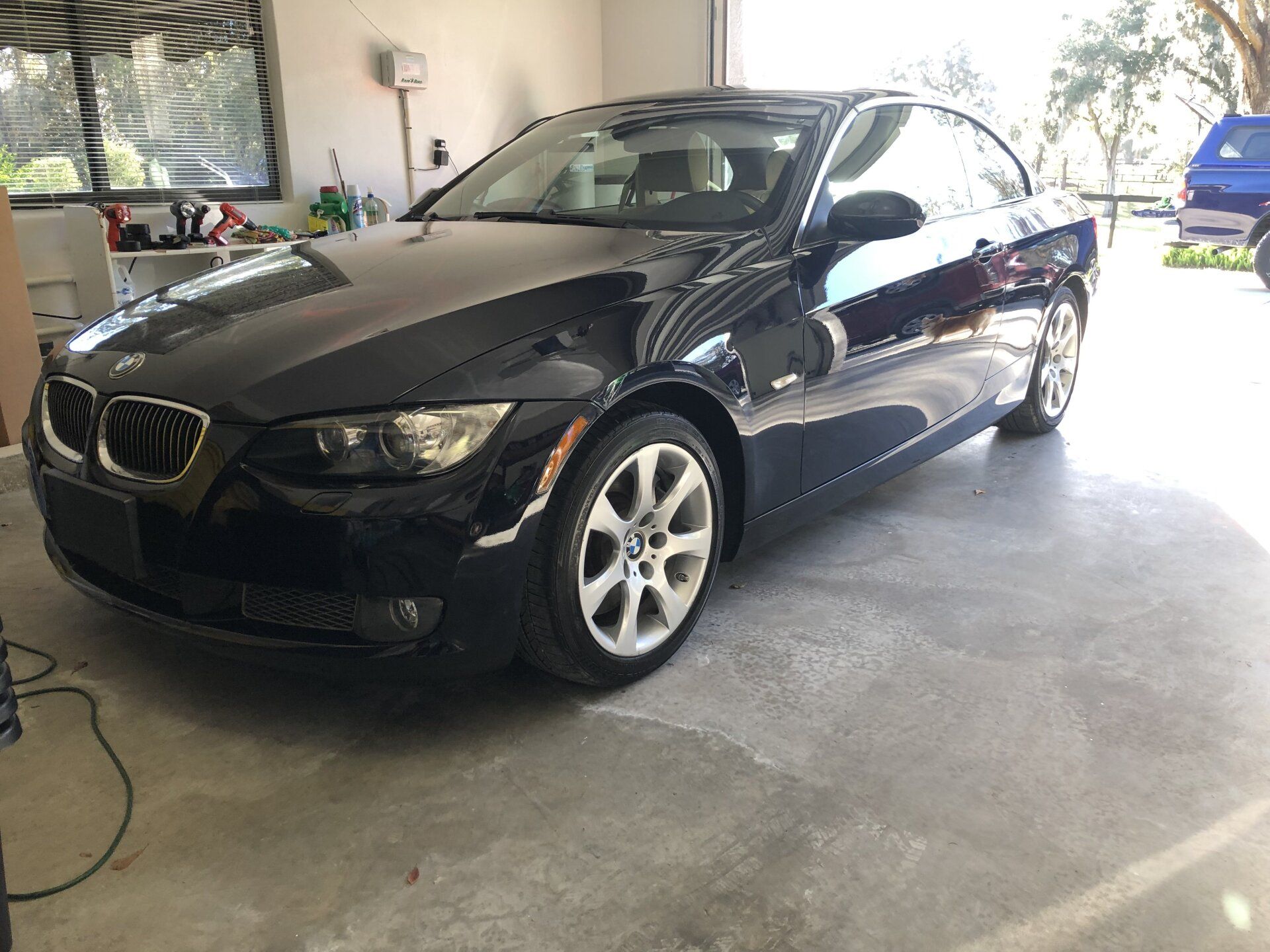 A black bmw 3 series coupe is parked in a garage.