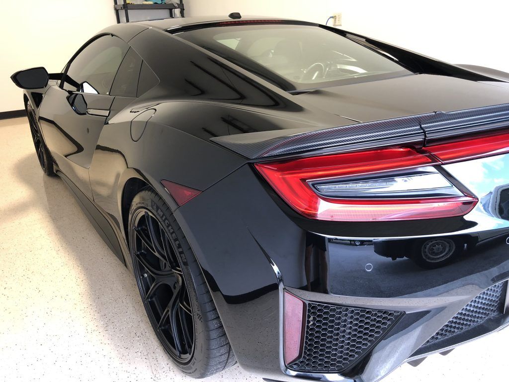 A black sports car is parked in a garage.