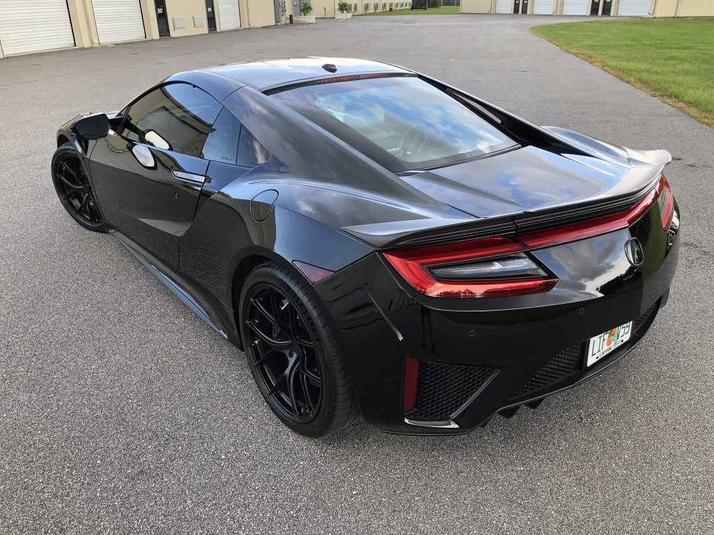 A black sports car is parked in a driveway.