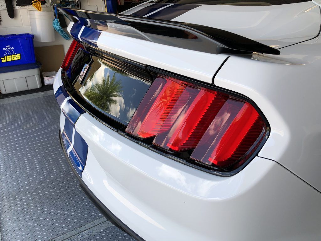 A white ford mustang is parked in a garage.
