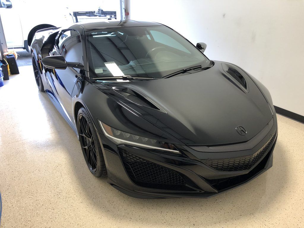 A black sports car is parked in a garage.