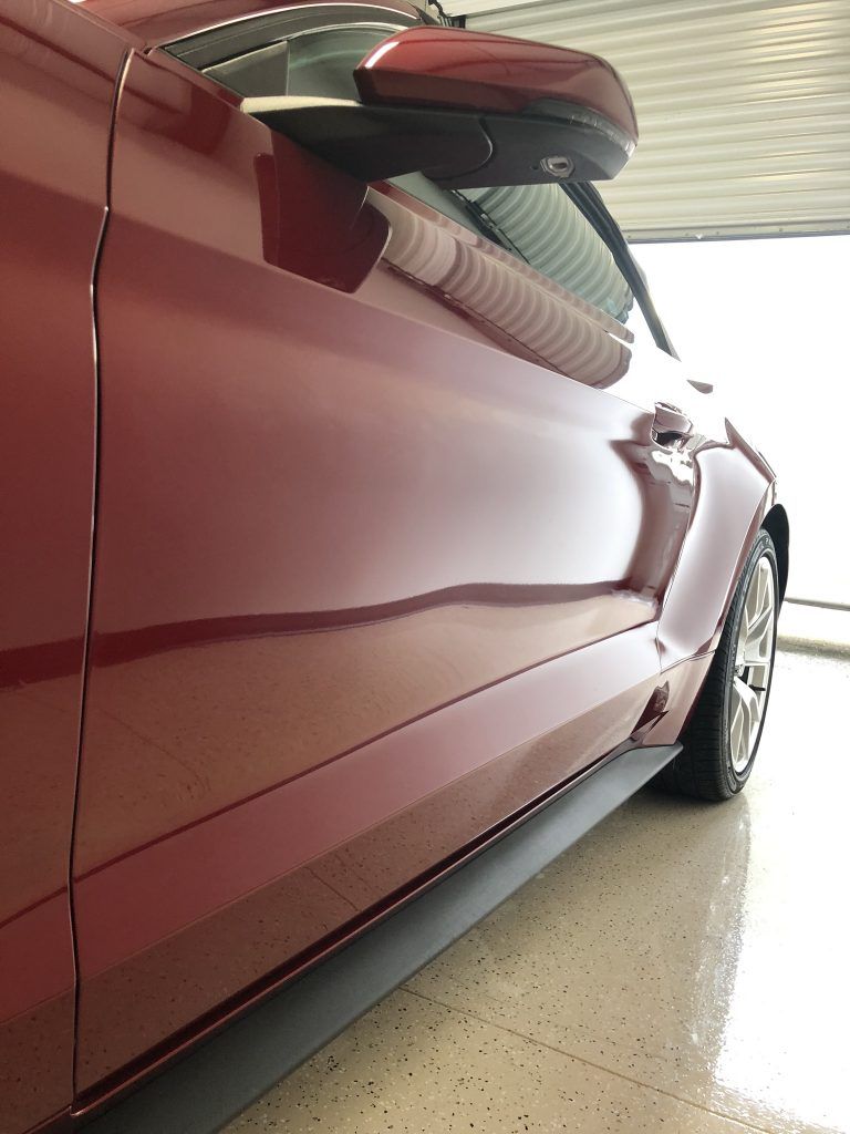 A red car is parked in a garage with the door open