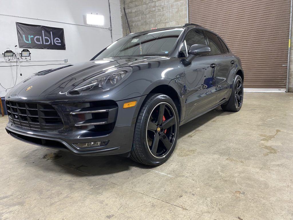 A black porsche macan turbo is parked in a garage.