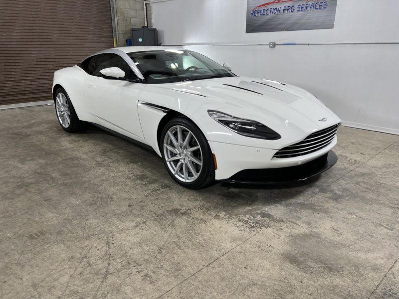 A white aston martin db11 is parked in a garage.