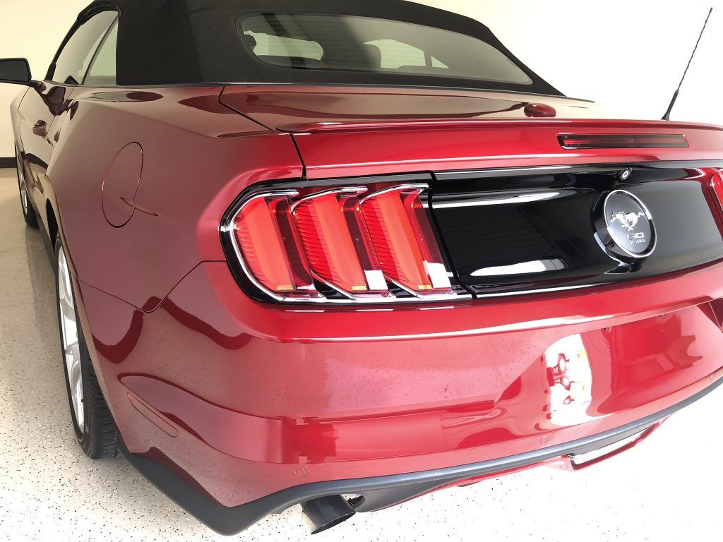 A red mustang convertible is parked in a garage.