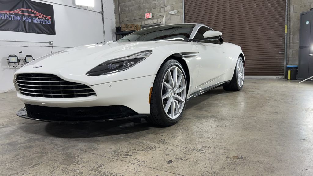 A white aston martin db11 is parked in a garage.