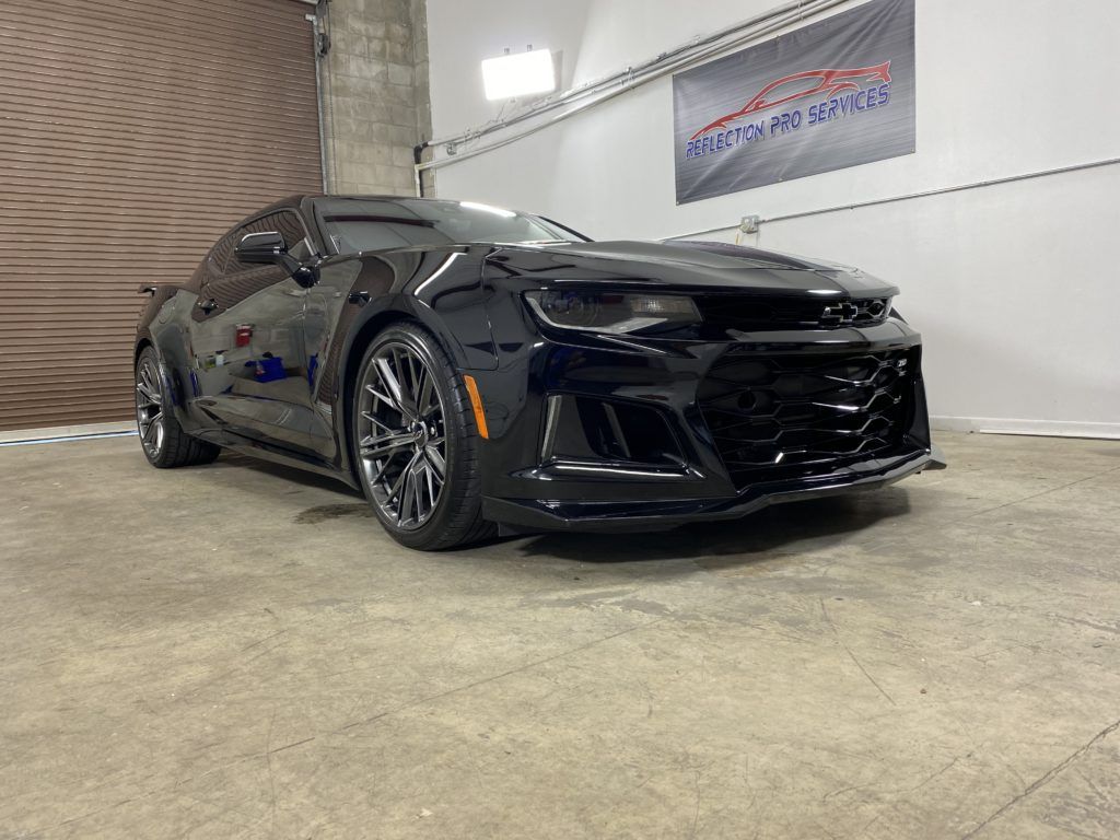 A black chevrolet camaro zl1 is parked in a garage.