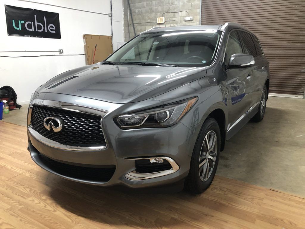 A gray infiniti qx60 is parked in a garage.
