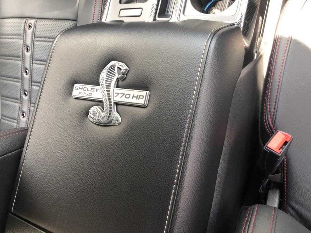 A black leather arm rest with a cobra emblem on it