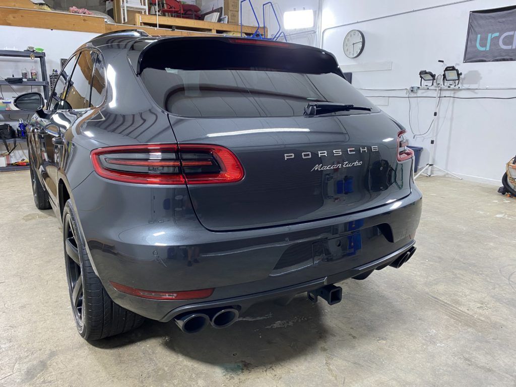 A gray porsche macan is parked in a garage.