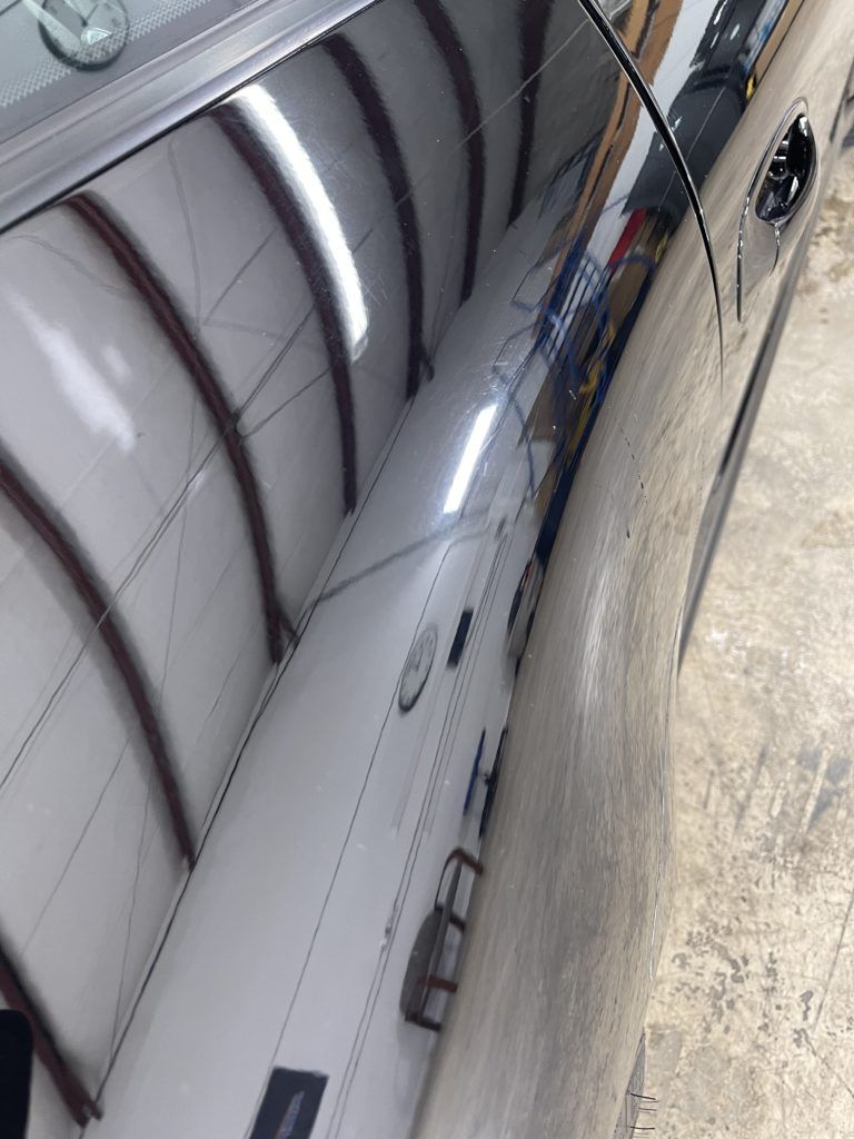 A close up of a car 's side with a reflection of a building.