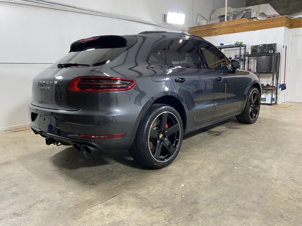 A gray porsche macan is parked in a garage.