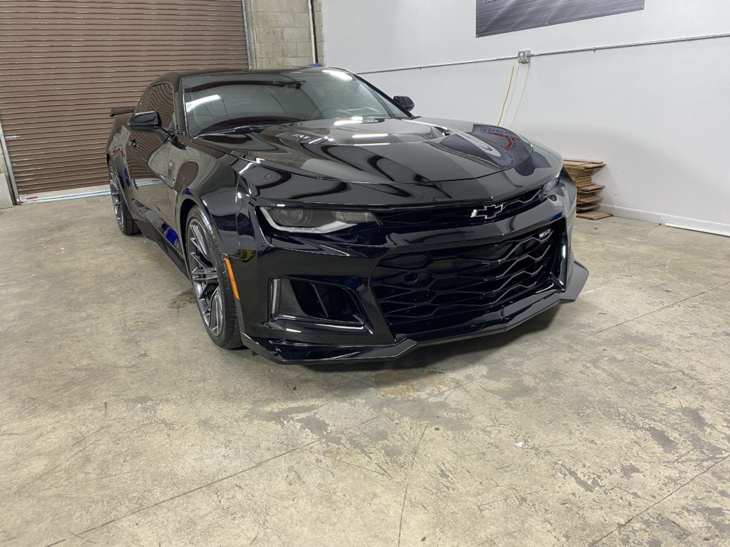 A black chevrolet camaro zl1 is parked in a garage.